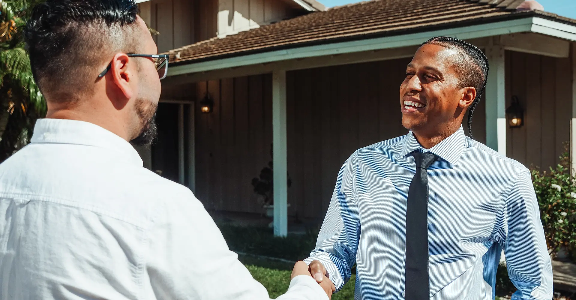 successful male real estate agent in tie smiling shaking hands with customer successful male real estate agent in tie smiling shaking hands with customer