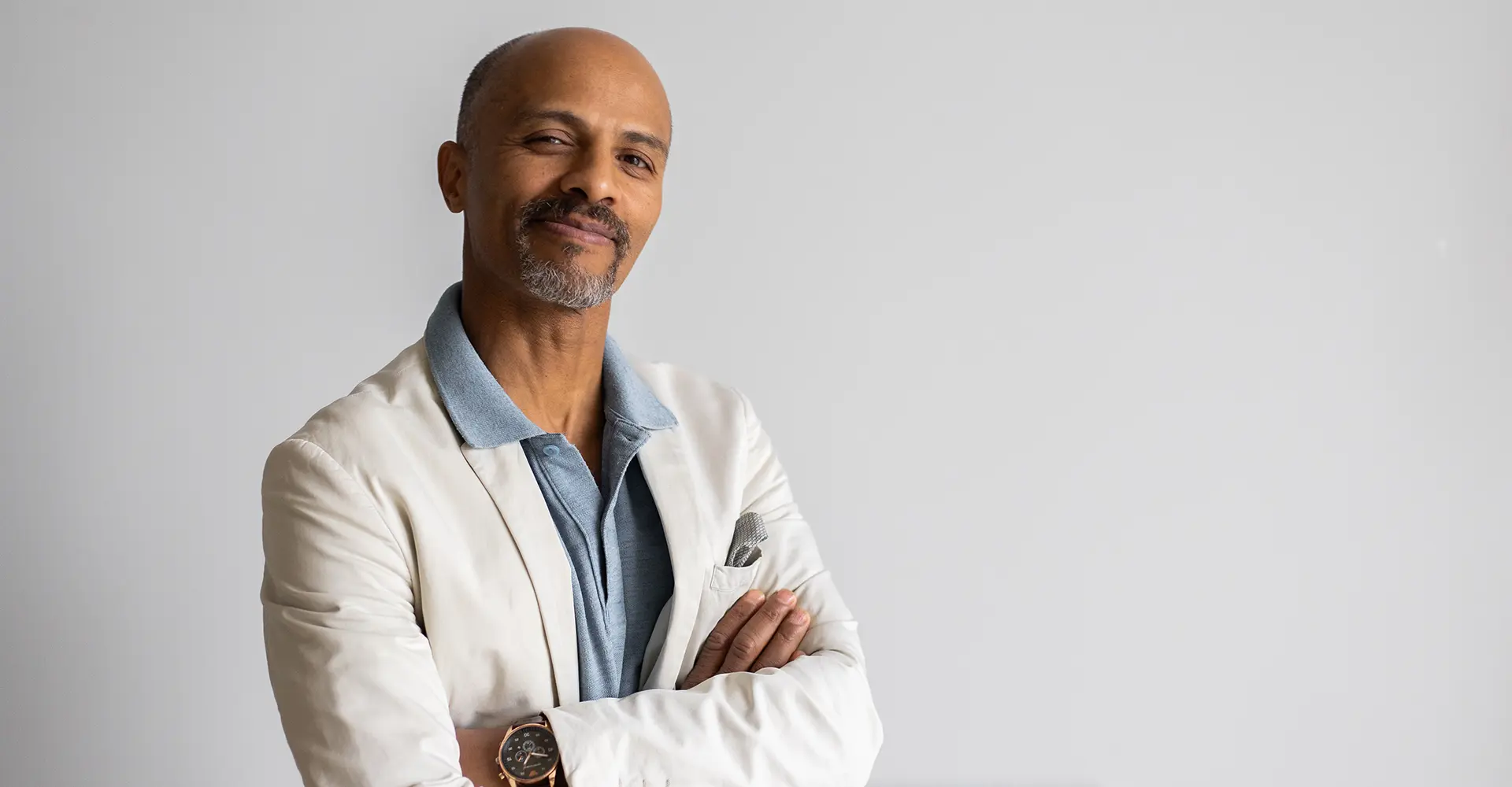 bald-man-in-white-blazer-with-arms-crossed-smirking-confidently